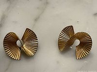 Top-down view of both earrings on marble surface showing spiral form