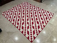 Full view of red and white quilt laid flat on floor