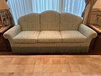 Front view of sofa showing scalloped back and fringe skirt