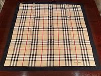 Full view of square scarf laid flat on table showing overall check pattern and navy border