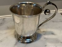 Front view of cup showing polished body, flared rim and small dents on side