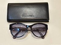 Front view of sunglasses placed in front of closed Chanel case