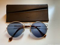 Front view of sunglasses and Dior case against neutral background