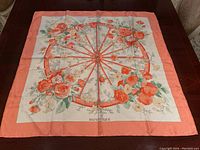 Full view of the scarf laid flat showing peach border and central floral wheel motif