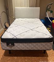 Assembled bed with linen headboard, platform base and mattress from front view