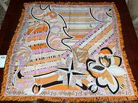 Full view of square scarf laid flat showing overall pattern, colors and fringe.