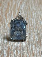 Front view showing emerald-cut aquamarine set in prong mount with triangular accent above