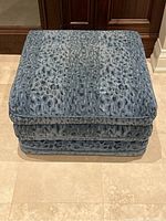 Front view of square ottoman showing stacked cushions and fabric pattern