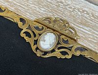 Close-up of gold filigree frame and oval cameo