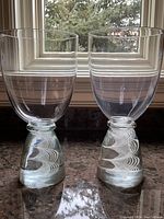 Pair of clear glass goblets with conical latticino bases set on windowsill