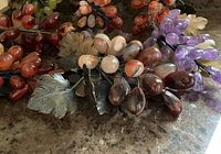 Close-up of mixed-color stone grape clusters showing leaves and wired stems.