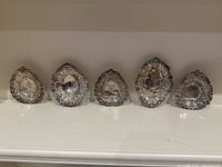 Five sterling silver nut dishes lined up side by side