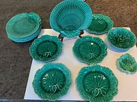 Overview of 15 pieces, including 8 shell plates on left, 5 leaf plates front, bowls on right