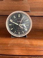 Full view of the round Big Ben Westclox clock on a wooden surface showing the time and clock body.