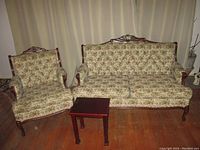 Full set showing loveseat, single armchair, and small side table on wood floor with curtain backdrop.