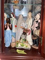 Front view of the 8 figurines arranged in a display cabinet.