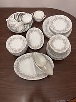 Full set of fine china dishes arranged on table showing variety of plates, cups, bowls, and serving platters.