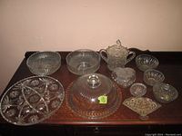 Front view of the lot showing all glassware and serving dishes arranged on a wooden table with clear visibility of patterns and shapes