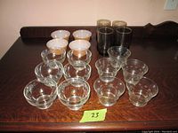 Overview photo of all glassware items on a dark wooden table, showing 9 clear bowls, 4 white bowls, and 4 smoked tumblers