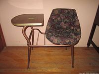 Side view of the MCM style swivel telephone table showing the floral upholstered swivel seat, metal frame, and wood veneer table surface with brass trim.