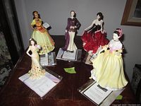 Five figurines arranged on table with certificates