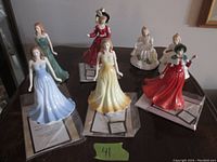 Six figurines displayed on table with paperwork