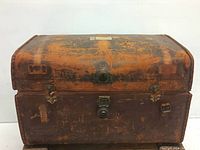 Full view of antique leather travel trunk showing overall condition and metal latch closures.