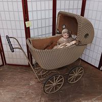 Side view of wicker pram stroller with one doll inside