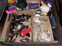 Overview of boxed costume jewelry and novelty items including chains, earrings, pendants and a small plush toy