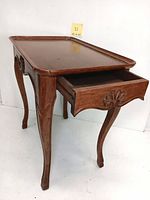 Full view of the table with drawer partially open showing the wood grain and carved front detail.