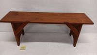 Front angle view of the wooden pine bench showing the rectangular seat and angled support legs.