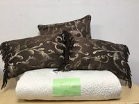 Overall view of white quilted bedspread with the three decorative pillows arranged on top.