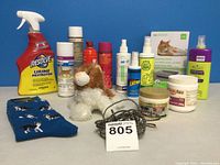 Wide shot of all cat care items including sprays, plush toy, socks, leash, supplements and box of liners arranged against blue background