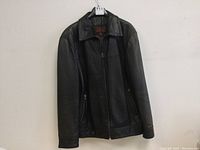 Front view of black leather jacket with zipper and pockets.