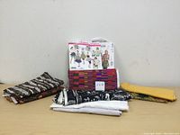 Photo of assorted folded cotton fabrics and vintage sewing patterns arranged on a surface against a white wall.