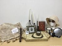 Wide view of decorative chess/checkers board frame, throw, flute, devotional book, hat with sunglasses, candle holders, picture frame, necklace, and watch.