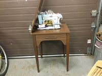 Photo of Kenmore sewing machine mounted on wooden cabinet in garage setting