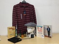 Full view of the lot showing shirt, cap on stand, books, grooming sprays and cologne, wallet, and comb