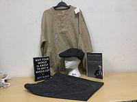 Full view of shirt, cap on mannequin head, folded jeans, and two books.
