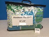 Photo of quilt folded in clear storage bag with label showing 60" x 88" size and handmade rag quilt text.