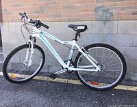 Side profile of the white RALEIGH Ladies Peak Mountain bicycle showing frame, wheels, and saddle.