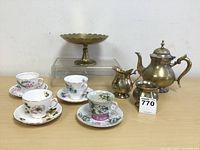 Full set of tea serveware comprised of teapot, creamer, sugar bowl, brass pedestal dish, and four china tea cup and saucer sets