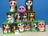 Front view of 13 TY Big Eye stuffed animals arranged in their green display boxes showing variety of colors and animal types.