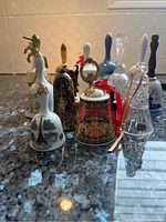 Front view of the group of 22 assorted decorative bells showing various designs, materials, and colors including porcelain, crystal, and painted decorations.