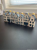 Front view of seven houses showing detailed façade designs, blue roofs, white bodies and yellow chimney stoppers