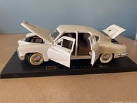 Full side and top view of white 1948 Tucker model car with hood, doors, and trunk open showing interior and detailed features.