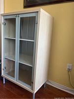 Light wood display case with two glass doors and shelves shown from an angled side view