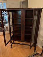 View showing front open doors revealing 4 solid wood shelves and decorative wood panel center