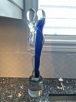 Full side view of the glass couple dancing statue on a counter with window background.