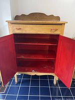 View of hutch with doors open showing red painted interior shelves and drawer above.